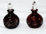 Par de perfumeiros de cristal na tonalidade rubi, lapidação estrela( 1 com tampa diferente). Alts. 11 cm