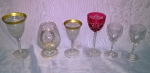 Seis taças , sendo: 1 para conhaque em vidro ,  taça de cristal lapidado na cor rubi, par de taças em cristal monogramado com coroa e 2 taças de cristal com borda em ouro  ( alguns com bicados).