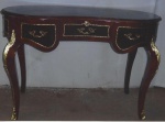 Mesa escrivaninha francesa em rádica, bombê, com 3 gavetas. Aplicações e guarnições em bronze dourado. Tampo de couro pirogravado em ouro. Medindo1,25 x 65 x 85 cm.