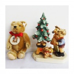 GOEBEL. Estatueta em porcelana policromada representando Crianças com árvore de Natal (19 cm)e um Urso de pelúcia( 20 cm).