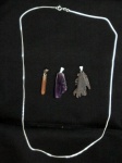 Três pendentes, sendo cristais "vassourinha", topázio imperial e ametista. Um cordão em prata.