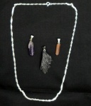 Três pendentes, sendo ametista, topázio imperial e cristal "vassourinha". Um cordão em prata.