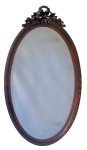 Espelho oval, 110x62cm, rica moldura em madeira nobre, orla decorada com friso em relevo, arrematado por exuberante florão, delicados entalhes e vazados: laços, guirlanda etc. Muito bem conservado.