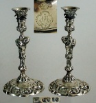 Par de castiçais em prata inglesa decorado com figura de querubim, med. 30 cm, peso aprox. 1.496 g