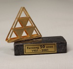 Escultura em metal dourado base em mármore negro com placa em metal "Fenaseg 50 Anos 1951-2001", med. 7 x 8 cm. Estado de conservação razoável (descolado)
