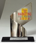Escultura em metal e base em material sintético "Top de Marketing SEGNEWS 2005", med. 25 cm. Estado de conservação bom