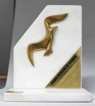 Escultura em bronze dourado sobre mármore branco "Troféu Gaivota de Ouro" 2007, med. 27 x 22 x 10 cm. Estado de conservação bom