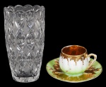 Duas peças sendo: vaso de cristal translúcido ( 21 cm) e pequena xícara com pires porcelana policromada e dourado( bocal com bicado- 4 cm)