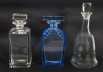 Tres garrafas em cristal, sendo 1azul e duas translúcidas.