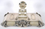 Tinteiro de prata portuguesa , contraste PORTO - REIS JOALHEIRO , decorado com volutas, concheado e cinzelados, recipiente de cristal (cristal com bicado). Medidas 6 x 39 x 24 cm. Peso aprox. 1,123 g