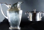 Duas peças em metal prateado , sendo: jarra MERIDIONAL( 21 cm) e açucareiro WOLFF.