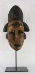 Imponente máscara africana de coleção em madeira entalhada sobre base em ferro, med. 56 cm