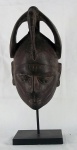 Imponente máscara africana de coleção em madeira entalhada sobre base em ferro, med. 56 cm