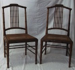 Par de cadeiras em  madeira entalhada imitando cana da India, assentos em palhinha. Acompanham almofadas .NO ESTADO. Medidas 85 x 50 x 48 cm.