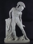Estátua em mármore branco de Carrara representando Gladiador Nú recostado sobre coluna, med. 66 cm de altura, 44 cm de largura e 22 cm de profundidade.