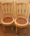 Par de cadeiras estilo francês em madeira entalhada e policromada , parte superior com para de pinhas no formato de abacaxis, assento em palhinha (palhinha no estado). Medidas 92 x 40 cm(APTO)