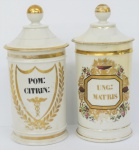 Par de potes de farmácia em porcelana francesa VIEUX PARIS do século XIX, com decoração a ouro, nome botânico das substâncias  "POM: CITRIN: " e  " UNG :MERC:D:", pintados em preto. Com restauro. Alt. 28 cm.