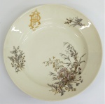 Prato brasonado em porcelana francesa, tendo ao centro galhos , flores e monograma com iniciais "B.P.". Diâm. 23 cm