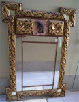 Antigo espelho de parede europeu, em madeira entalhada e dourada (ouro velho), detalhe com escultura, representando figura de anjo, espelho bisotado. Medida 1,46 x 1,02 cm.
