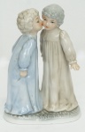 CAPO DI ANGELO. Grupo escultórico em porcelana espanhola, policromada, representando Crianças se beijando. Alt. 13 cm.
