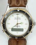 Relógio Technos Chronoalarm, caixa em aço com detalhes em dourado 38mm, pulseira de couro marrom, máquina sem funcionamento.
