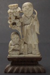 Grupo escultórico  em marfim representando Homem com criança . Acompanha peanha de madeira. Alt. total 10 cm.