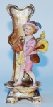 Floreira em porcelana com figura de menino com gaita de fole, medindo 16 cm de altura.