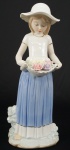 Estatueta em porcelana policromada representando Menina com cesto de rosas. Alt. 29 cm.