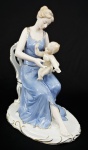 Grupo escultórico em porcelana policromada representando Mulher com criança. Medidas 24 x 18 cm.