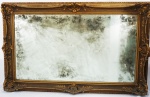 Espelho em cristal bizotado com moldura entalhada e dourada ( espelho com manchas do tempo). Medidas 136 x 88 cm.