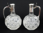 Galheteiro em grosso cristal composto de 2 garrafas, tampas em metal espessurado a prata, da marca francesa Christofle, alturas 16 cm.
