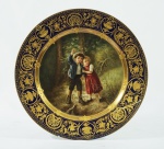 Prato decorativo em porcelana Hansel Gretel adornado com fig. de crianças e ricamente trabalhado nas bordas med. 24 cm de diâm. (apresenta lascado)