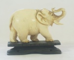 Escultura em marfim esculpido, representando Elefante, acompanha peanha em madeira, medindo 6x8 cm
