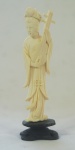Estatueta em marfim, representando Musicista (pequeno quebrado no cabelo) falta flor, acompanha peanha em madeira, medindo 13 cm