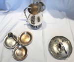 Lote composto por 3 (três) peças em metal prateado: jarra (alça solta, necessita restauro), porta petisqueira com 3 pratos  e quebra nozes necessitando de banho de prata.