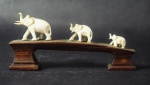 Grupo escultório em marfim chinês representando 3 (três) elefantes sobre ponte de madeira. Medida: 4x9cm.
