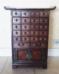 Mini armário porta chá  em madeira com vinte gavetaspequenas, duas gavetas maiores e duas portas, puxadores, espelho e dobradiças em metal. Medida: 69 x 51 x 24 cm.