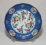 Prato redondo em porcelana chinesa com decoração floral em tons de azul e borda ondulada medindo 31cm de diâmetro.