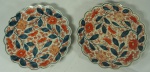 Par de pratos em porcelana japonesa Satsuma decorados com folhas e flores em tons de azul cobalto e rouge de fer, medindo 25cm de diâmetro. Apresentam no verso pinturas de aves no paraíso.
