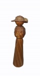 Figura feminina em palha e madeira com chapéu, medindo 14,5 cm de altura e 3,5 cm de diâmetro na base.