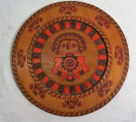 Medalhão em madeira com pintura colombiana típica, medindo 30 cm de diâmetro.