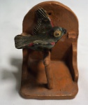 Escultura em barro cozido representando poleiro com papagaio, medindo 9 x 7 x 7 cm. No estado, apresenta pequeno quebrado.