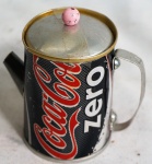 Pequeno bule confeccionado em lata de refrigerante, medindo 10 cm de altura.