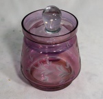 Bombonier em vidro lilás lapidado com folhagens, medindo 18 cm de altura. Borda apresenta bicados, tampa adaptada.