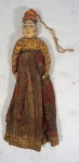 Boneca indiana com cabeça em madeira policromada e corpo em tecido estampado, medindo 39 x 11 cm. Acompanha barbante para pendurar.