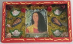 Quadro envidraçado com colagens de vários materiais, estampa central da Frida Khalo, e haste para ser pendurado. Medindo em seu total 11 x 18,5 x 3 cm.