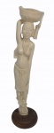 Escultura  em marfim representando Africana com balaio na cabeça com base em madeira. Assinada ESABE NG.  Alt. 29 cm.