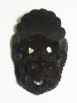 Miniatura de máscara esculpida em madeira, medindo 18 x 12 cm.