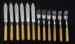 Conjunto para sobremesa em prata contrastada com cabo de marfim , composto de 6 facas e 6 garfos. Peso total aprox. 560 gr.