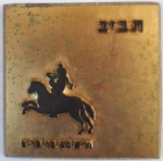 Antiga medalha quadrada em metal dourado tendo em uma das faces figura humana sobre um cavalo e no verso inscrição em idioma oriental. Peso: 27,28 g. Dimensões: 4x 4 cm.